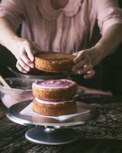 woman frosting Strawberry cake with Strawberry Cream Cheese Frosting