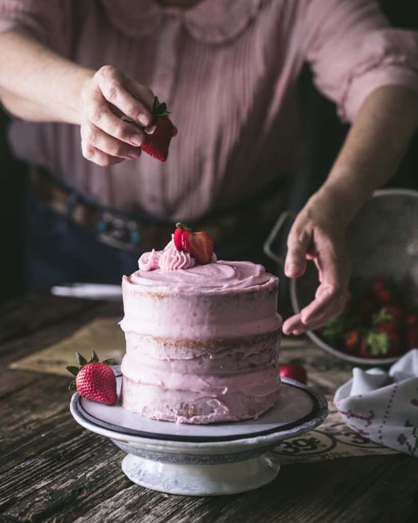 woman garnishing cake on plate