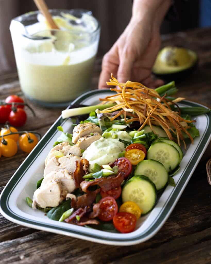 hand pushing forward a platter of salad