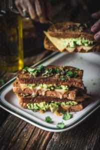 woman serving Chile cheddar grilled cheese with avocado
