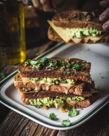 woman serving Chile cheddar grilled cheese with avocado